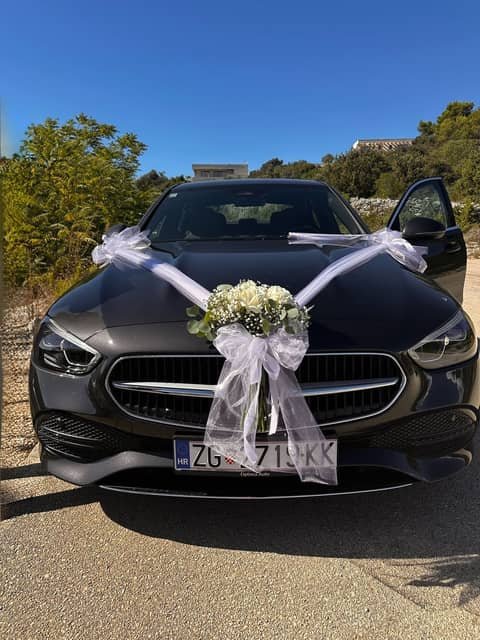 Svadbeni automobil ukrašen bijelom vrpcom i kiticom gipsofile