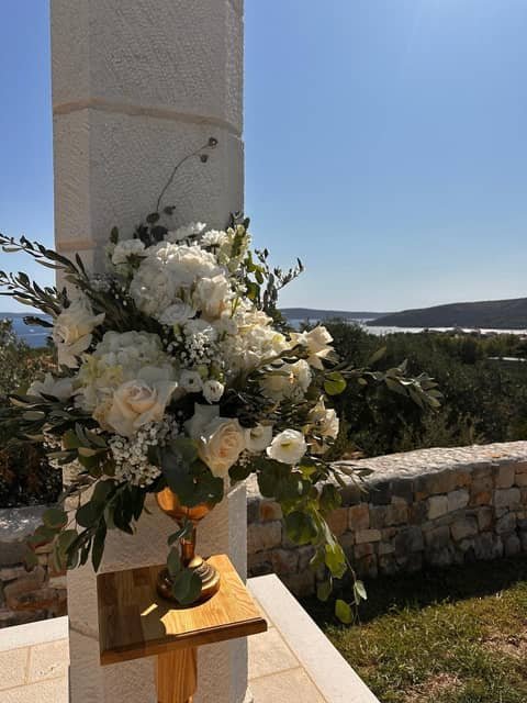 Buket od bijelih ruža i masline na kamenom zidu iznad brda